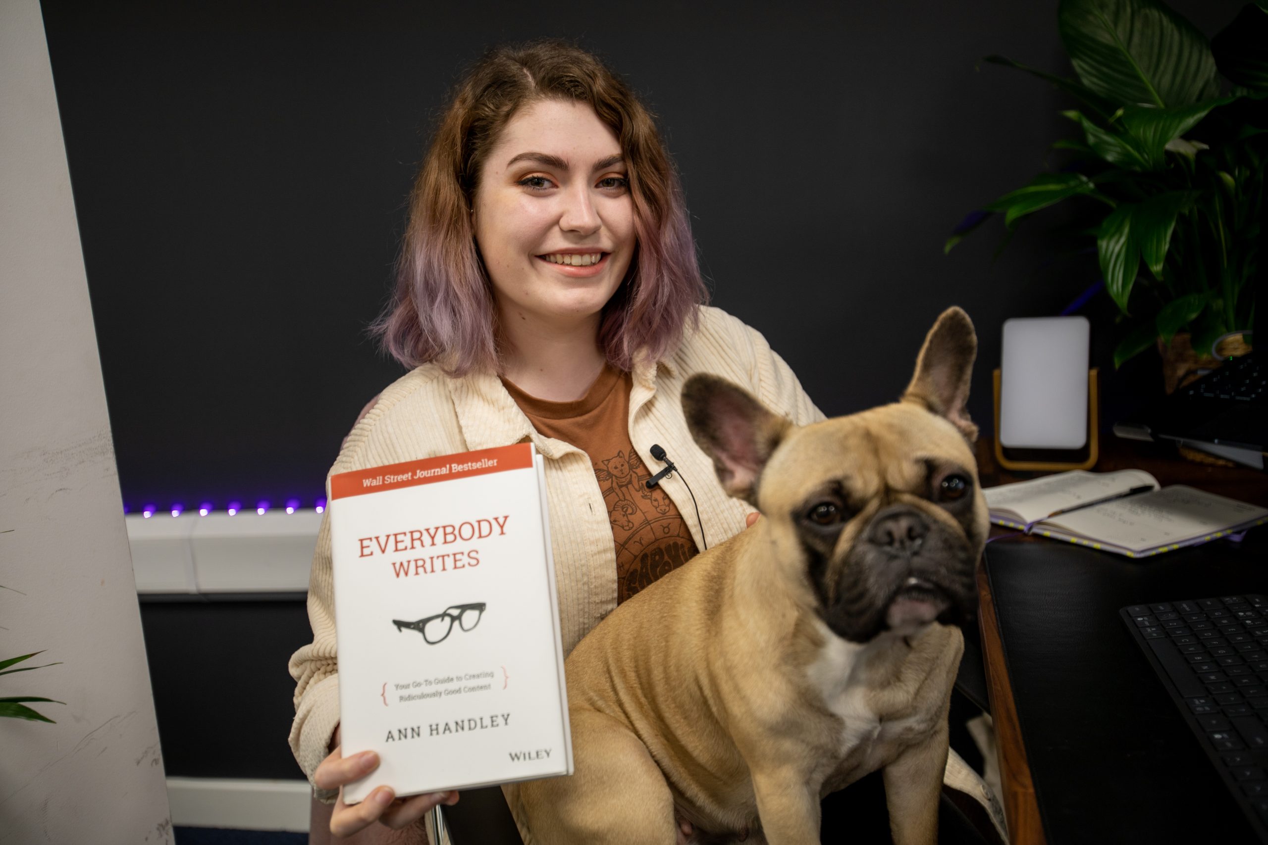 Soph holding 'Everybody Writes' with a brown french bulldog on their lap
